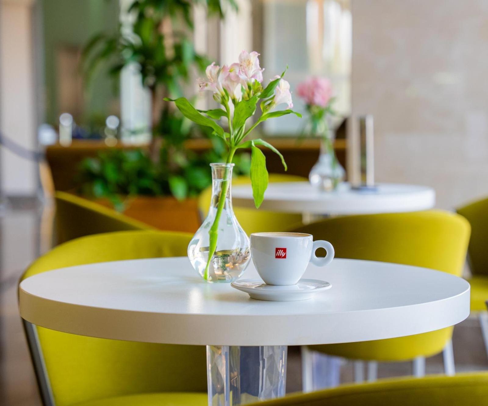 Marina Hotel Kuwait City Exterior photo A table with a flower vase and a cup of coffee